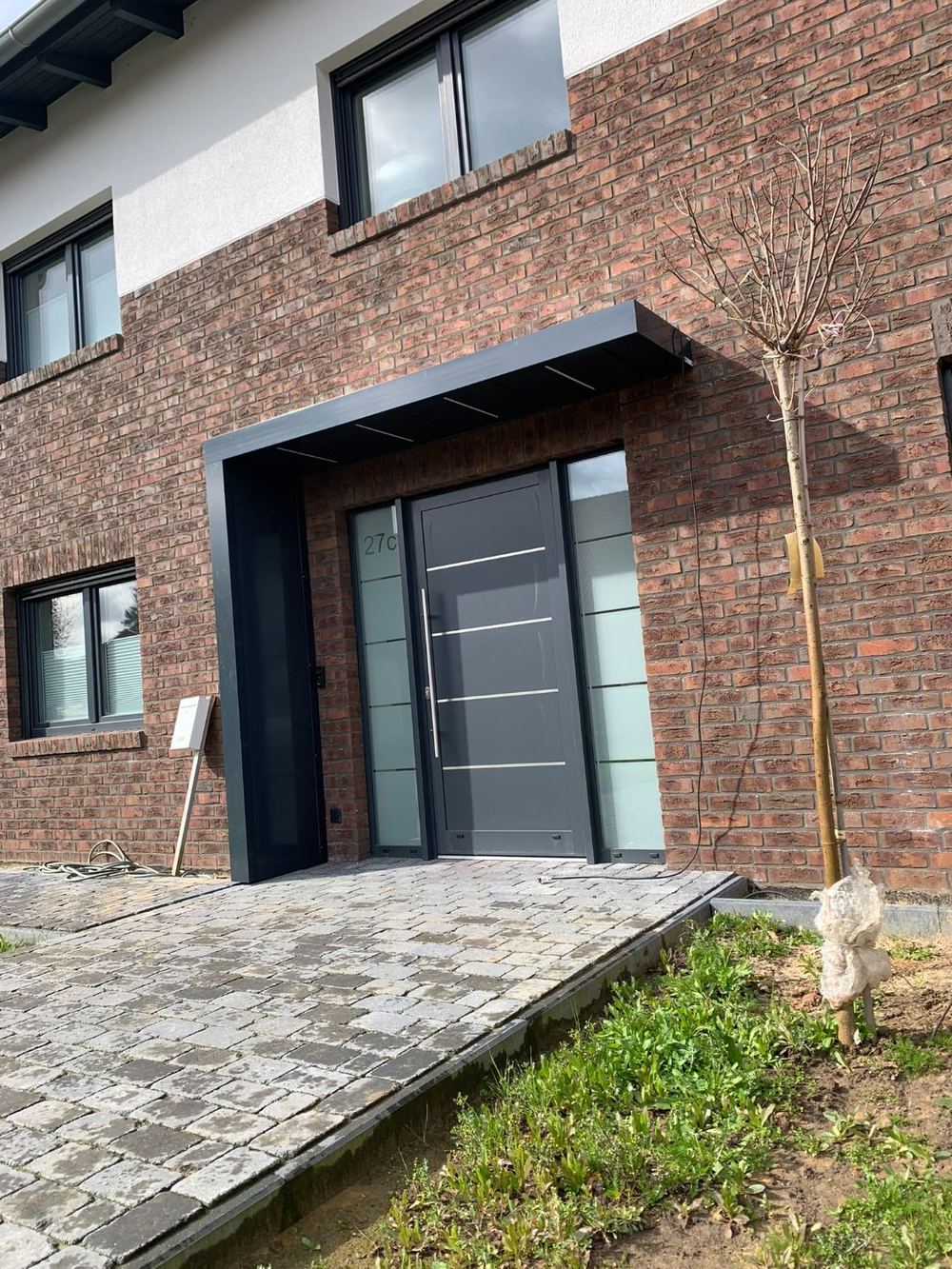 Schwarzes Vordach über Haustür an Klinkerfassade, A&S Montagebetrieb Stolzenau